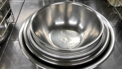 A set of nesting metal mixing bowls on a metal counter.