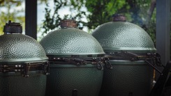 Three green kamado grills next to each other outside.