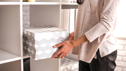 woman putting cardboard box on shelf