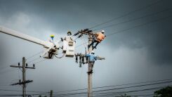 Electrical workers climbing a utility pole to change a power line