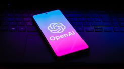 A phone showing the OpenAI logo lying on a laptop