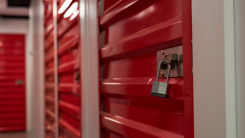 A line of storage units with red metal doors and padlocks