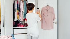 A woman taking a photo of a garment while cleaning out her closet