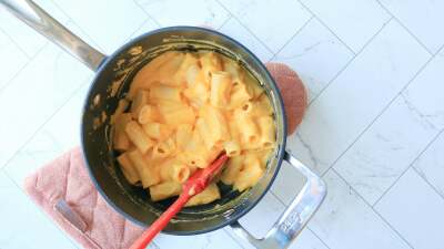 Macaroni with yellow sauce in a pot on a countertop.