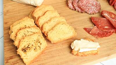 Sliced biscuit crackers on a cutting board with meats and cheeses.