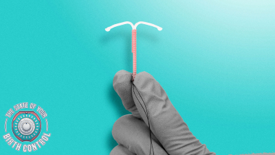 A hand in a latex glove holding up an IUD