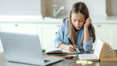 Girl doing homework with laptop and notebook