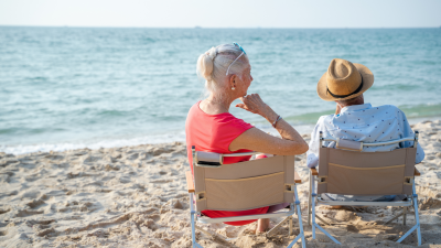 elderly couple sitting on the beach together