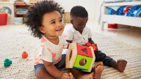 two toddlers playing with toys on the floor