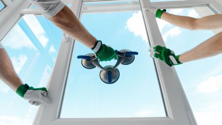 Workers installing new windows in a home as seen from inside