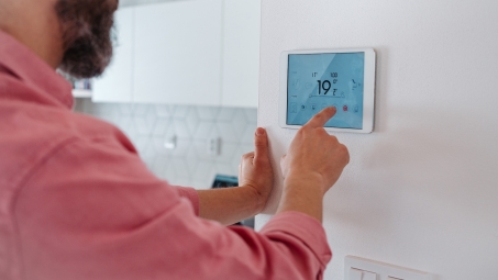 man adjusting smart thermostat