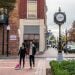 A couple walking their dog in a quaint downtown area