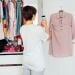 A woman taking a photo of a garment while cleaning out her closet