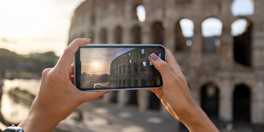 A person takes a photo of the Coliseum with their phone