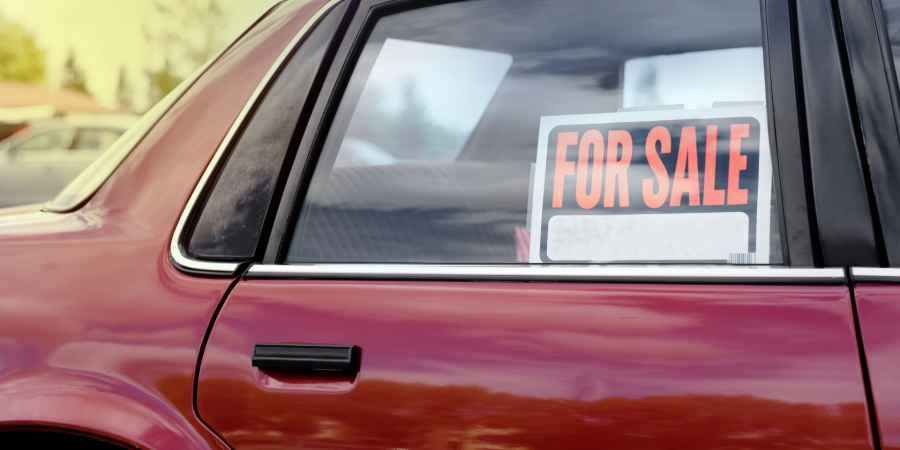 for sale sign in window of a used red car