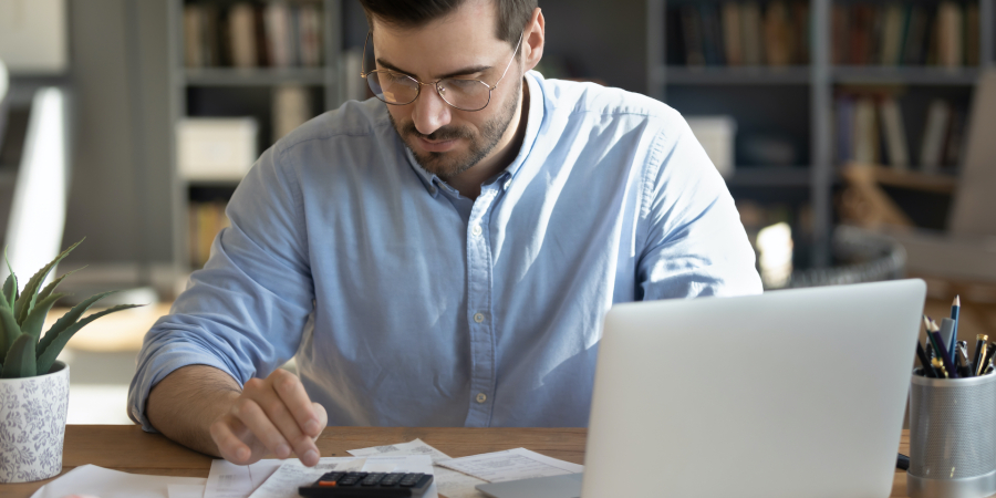 man looking at accounts on computer and using calculator