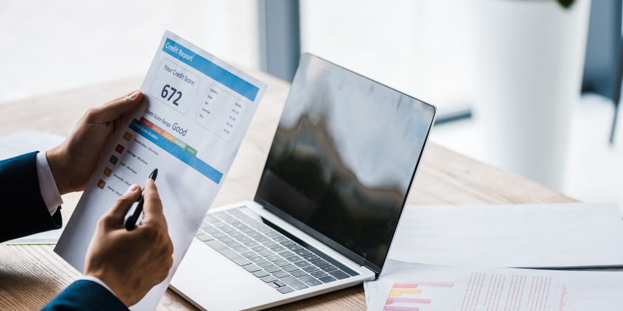 Person holding credit report in front of computer 